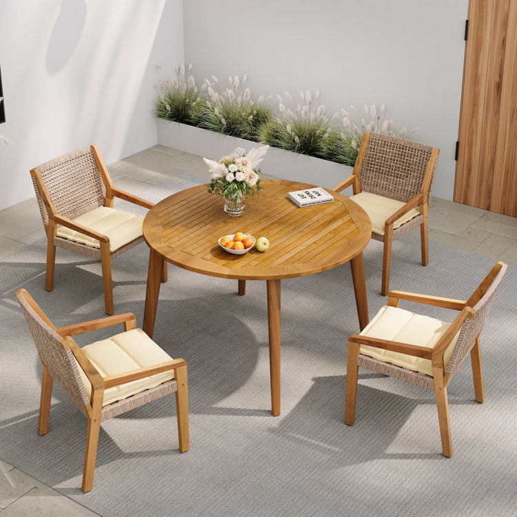 Acacia and Wicker Outdoor Dining Set — Round acacia table and four wicker armchairs with cream cushions for outdoor dining