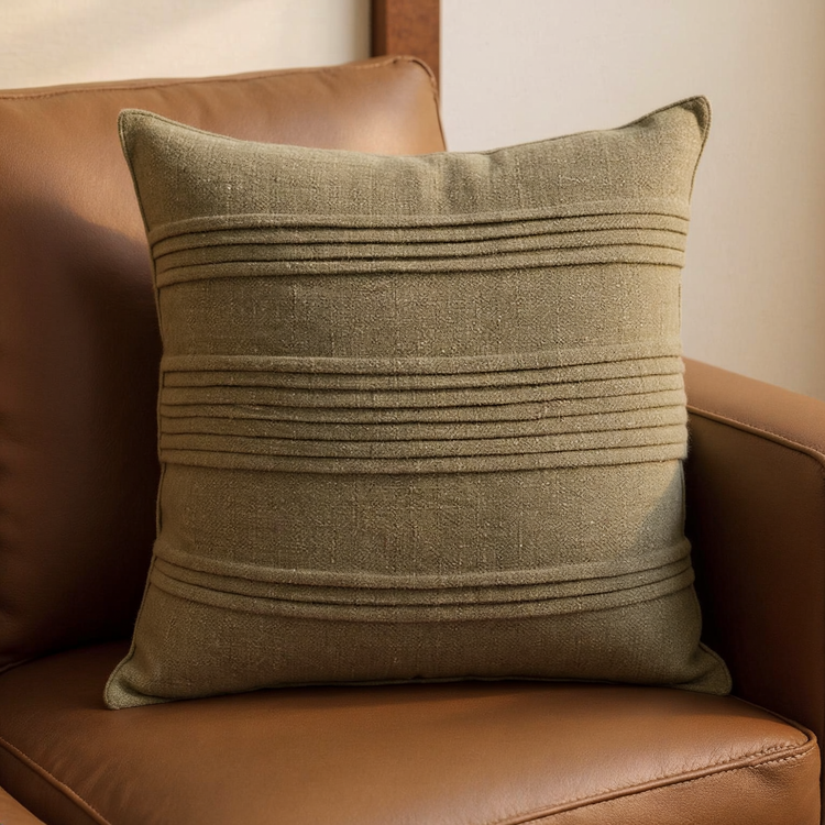 Moss Green Pintuck Linen-Blend Pillow Cover with horizontal pintuck bands on a cognac leather lounge chair