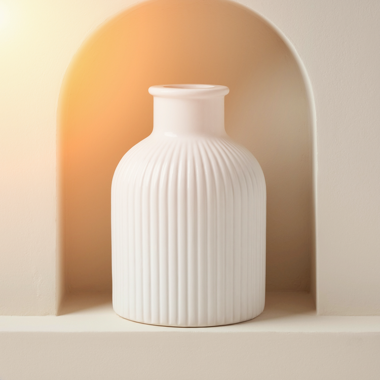 Matte White Ribbed Gypsum Bottle Vase in a cream plaster niche with warm natural side light