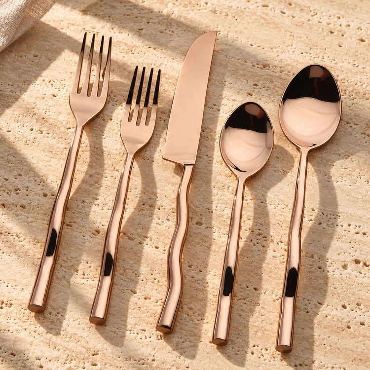 Wavy Handle PVD Bronze Flatware Set on a sunlit pale travertine counter