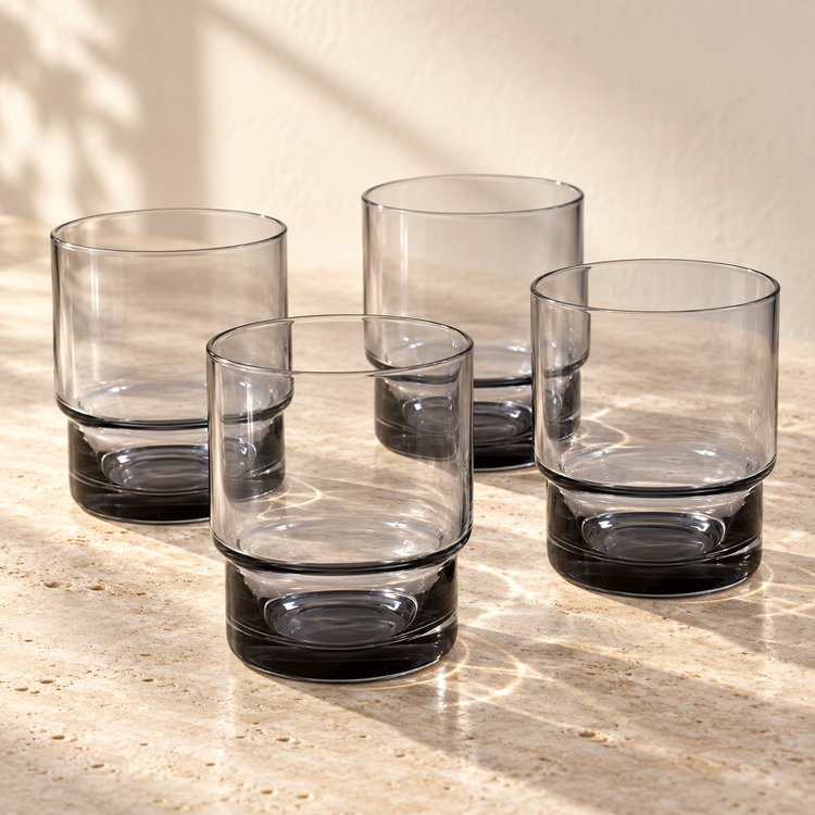 Smoked Glass Rocks Glass Set empty on honed travertine in warm side light