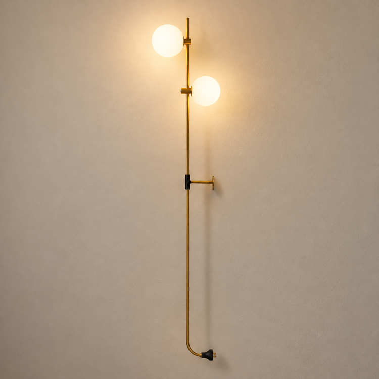 Gold-Finish Double Globe Wall Sconce illuminated against cream plaster