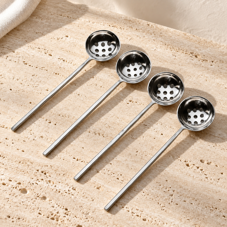 Perforated Steel Olive Spoon Set on a sunlit pale travertine counter