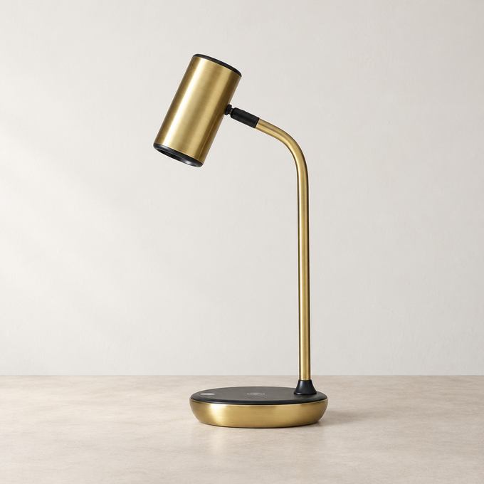 Brass LED desk lamp with an adjustable shade and wireless charging base