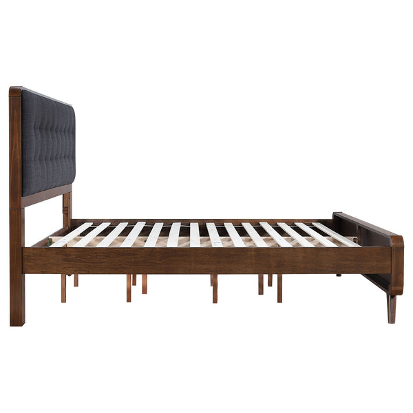 Side view of a walnut-tone bed frame showing wood slats, center supports and a tufted headboard.
