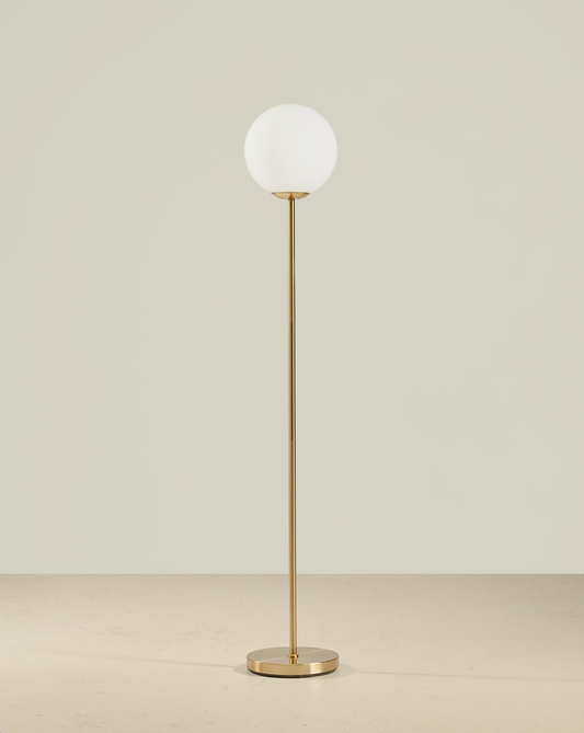 Brass floor lamp with a white globe shade, slender stem and round brass base