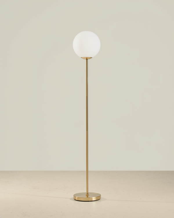 Brass floor lamp with a white globe shade, slender stem and round brass base