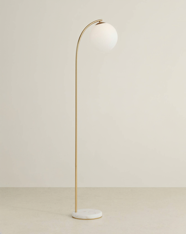 Brass arc floor lamp with a white globe shade and round white marble base