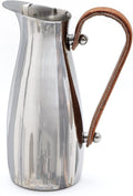 Polished Steel Leather-Handle Pitcher styled on a countertop with fresh botanicals