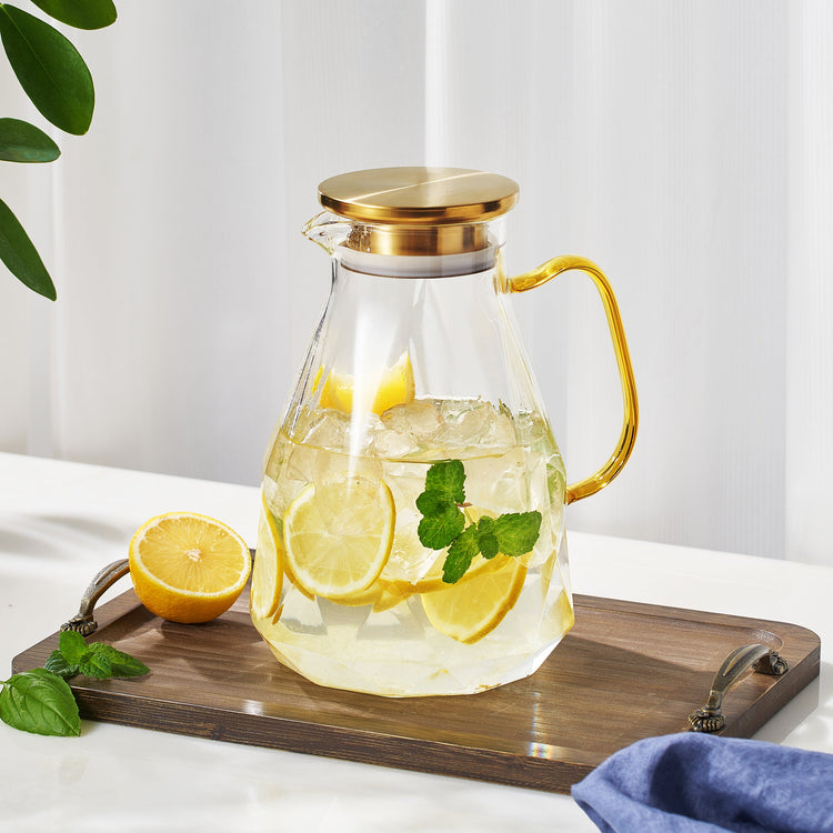 Faceted Glass Pitcher Gold Lid — Faceted clear glass pitcher with amber handle and gold-tone lidded strainer spout