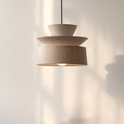 Tiered Organic Cotton Pendant Lamp glowing on a bedside table with books