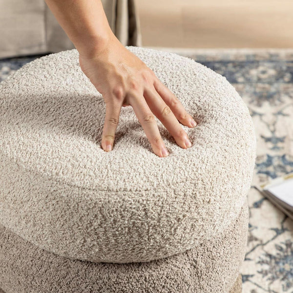 Person touching beige ottoman, round