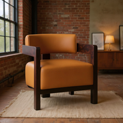 Cognac faux leather barrel accent chair with dark wood arms in a warm brick loft