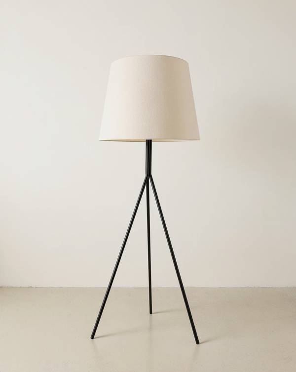 Black tubular tripod floor lamp with a gently tapered cream fabric shade