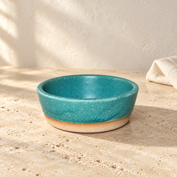 Glazed Ceramic Snack Bowl — Single / Ocean Teal, arranged on pale travertine in warm natural light