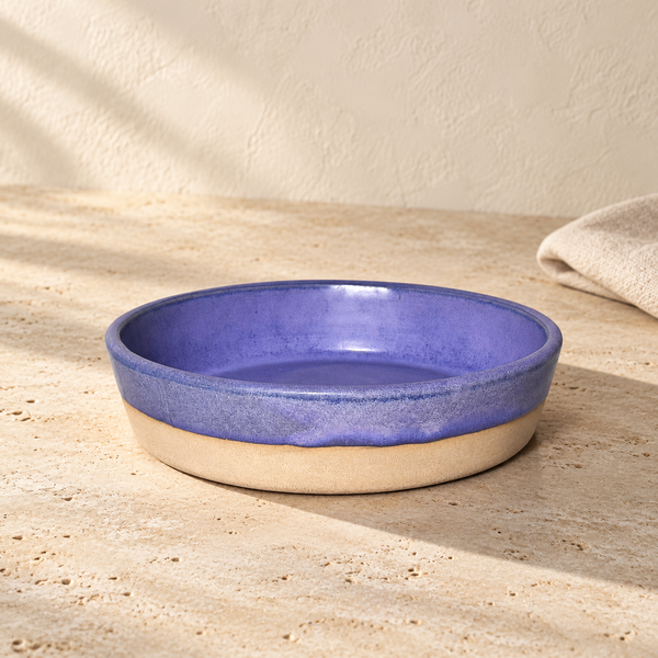 Glazed Stoneware Side Bowl — Single / Periwinkle Violet, arranged on pale travertine in warm natural light