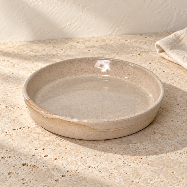 Hand-Finished Stoneware Side Plate — Single / Sandstone Clear, arranged on pale travertine in warm natural light