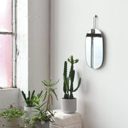 Brass-Hung Oval Wall Mirror hung above a console table with ceramics