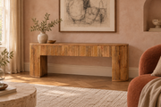 Brown fluted mango wood media console with rounded end supports in an Artisan living room with textured plaster, rust upholstery and warm parquet flooring
