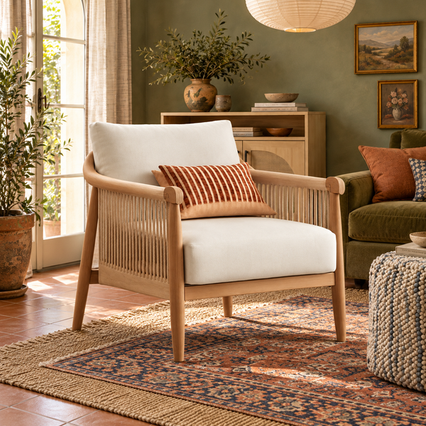 Cream-cushioned braided cord wood-frame accent chair with a rust striped pillow in a Boho room with olive walls and layered patterned rugs