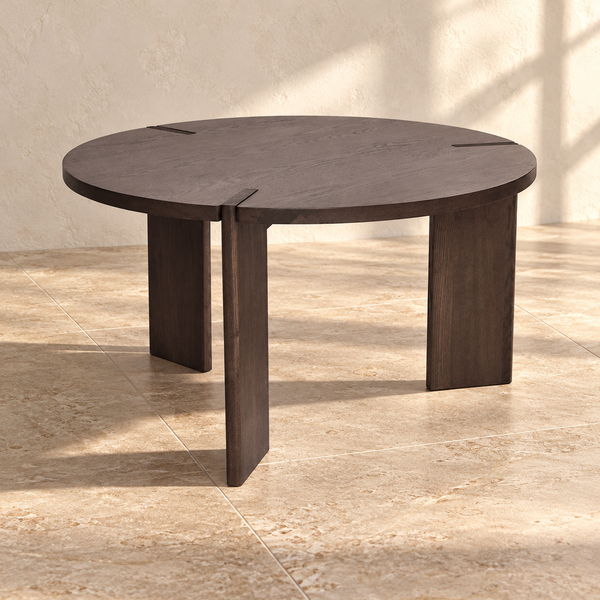 Dark Stained Ash Round Coffee Table against a cream limewash wall on a travertine floor in warm afternoon light