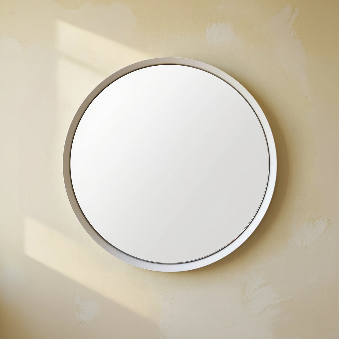 Spun Steel Round Wall Mirror against a cream wall with warm natural side light.
