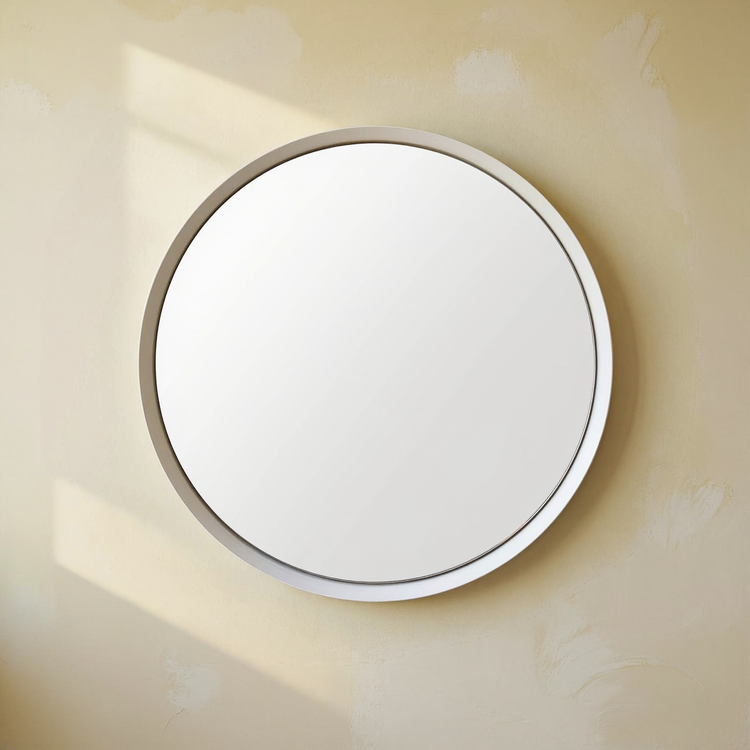 Spun Steel Round Wall Mirror against a cream wall with warm natural side light