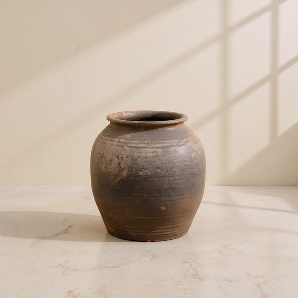 Antique-Finish Earthenware Belly Planter against cream microcement with warm steel-window grid shadows