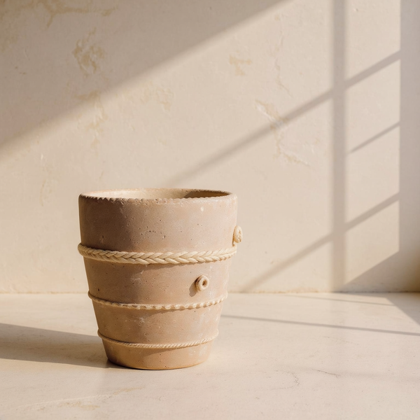 Rope-Banded Terracotta Planter against cream microcement with warm steel-window grid shadows