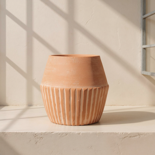 Fluted Terracotta Hand-Thrown Planter against cream microcement with steel-window grid shadows