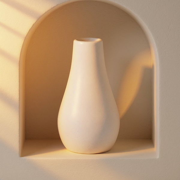 Matte White Hand-Cast Gypsum Bud Vase in a cream plaster niche with warm natural side light