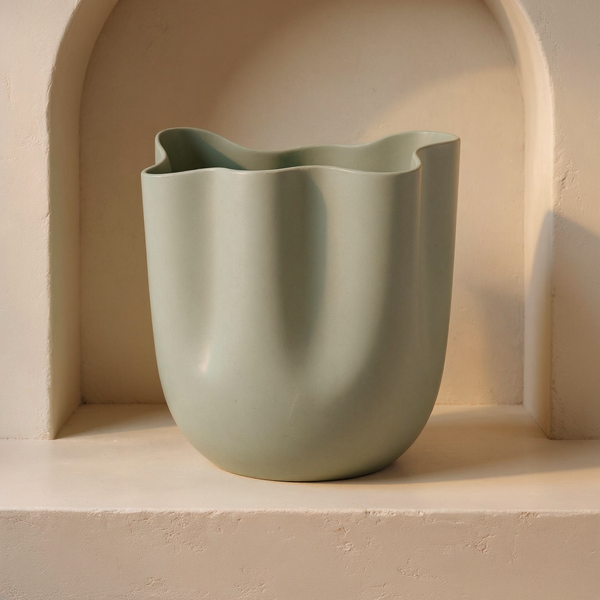 Asymmetrical Wave Rim Aluminium Vase in a cream plaster niche with warm natural side light