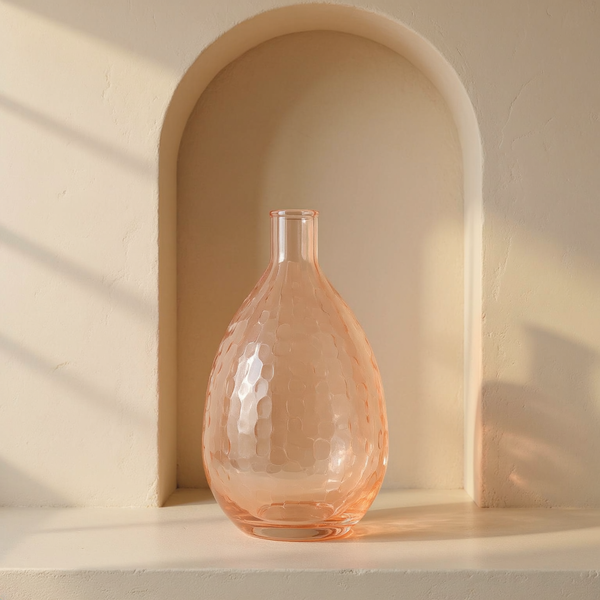 Peach Handmade Hammered Glass Vase in a cream plaster niche with warm natural side light