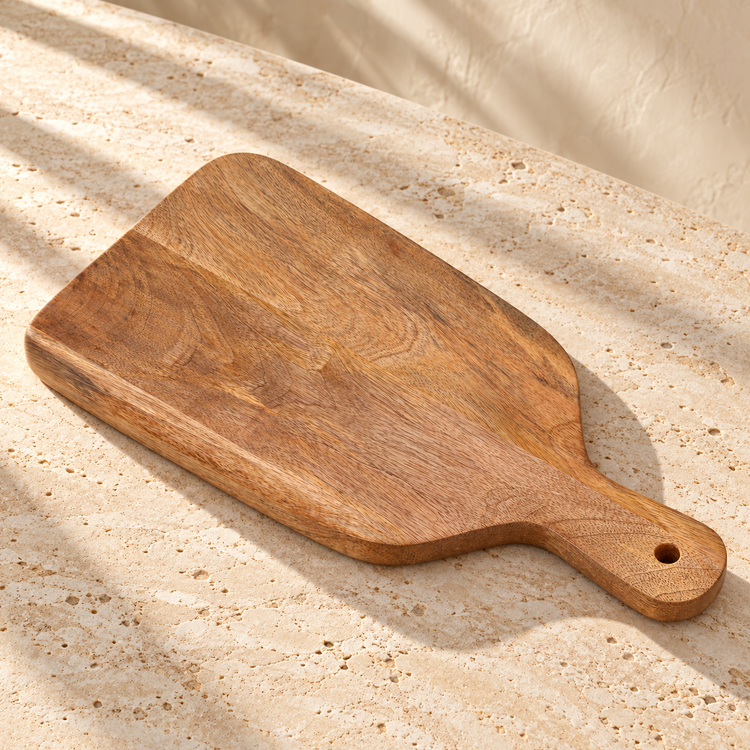 Natural Wood Serving Board with Handle — 17" x 9" on a sunlit pale travertine counter