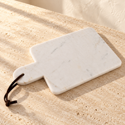 Marble Charcuterie Board with Leather Strap on a sunlit pale travertine counter
