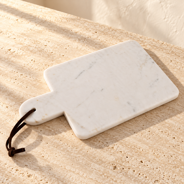 Marble Charcuterie Board with Leather Strap on a sunlit pale travertine counter
