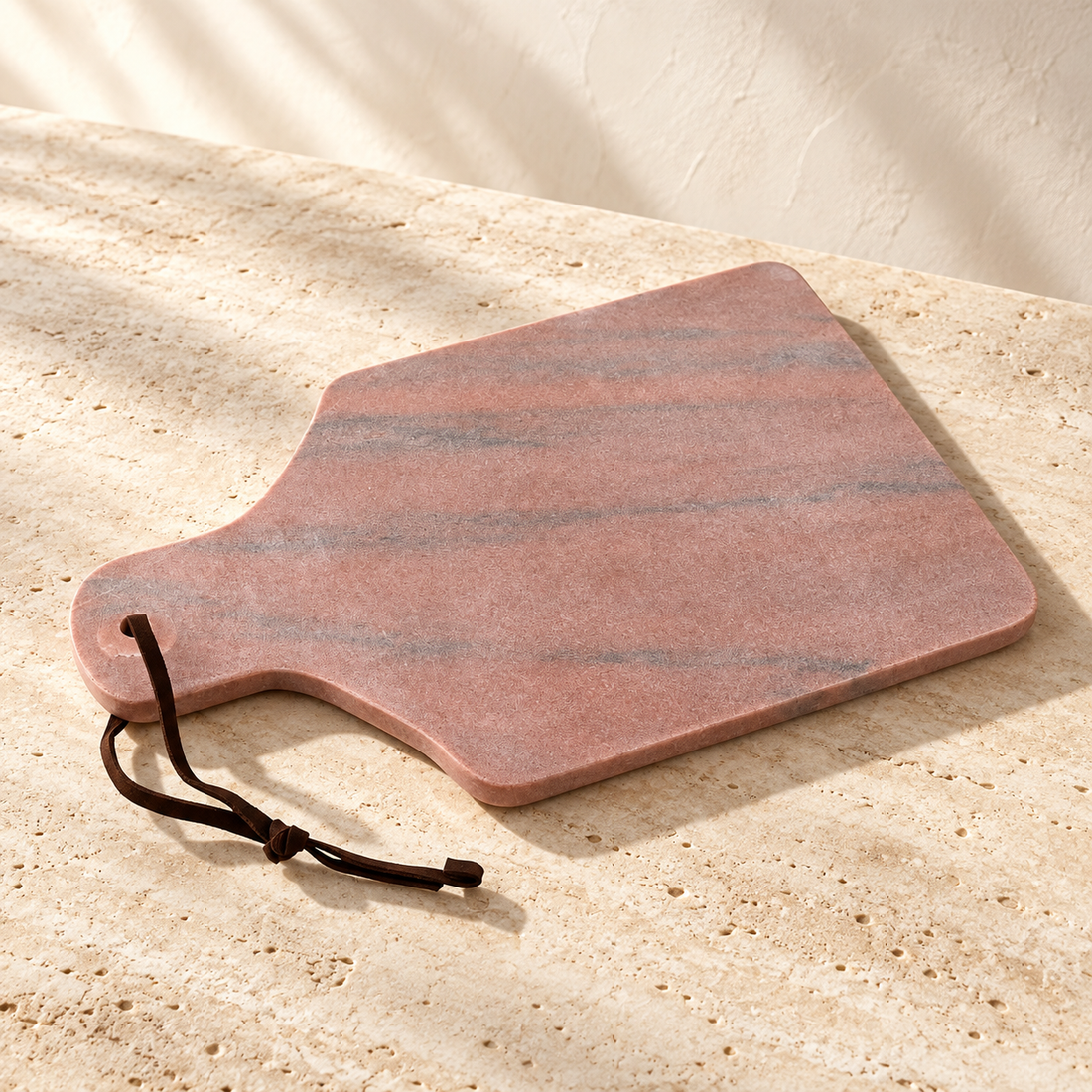 Rose Marble Paddle Serving Board on a sunlit pale travertine counter