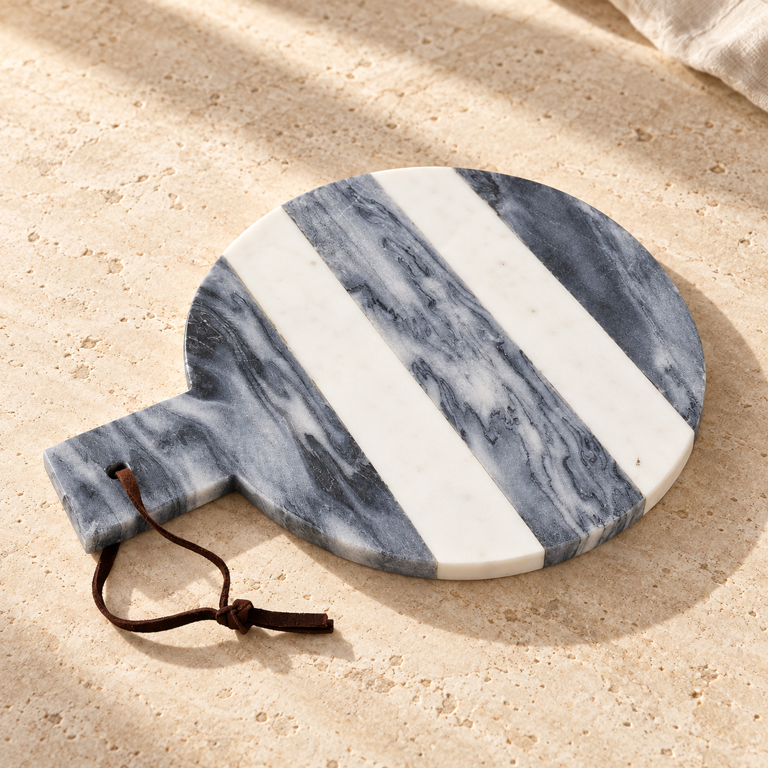Striped Marble Round Cheese Board on a sunlit pale travertine counter