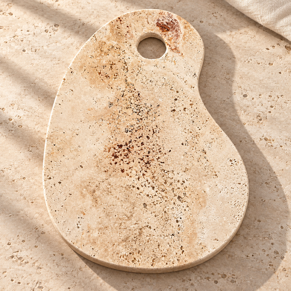 Pear-Shaped Travertine Stone Serving Board on a sunlit pale travertine counter
