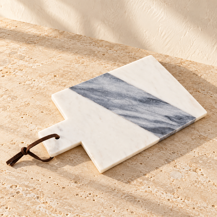 White and Gray Marble Paddle Serving Board on a sunlit pale travertine counter
