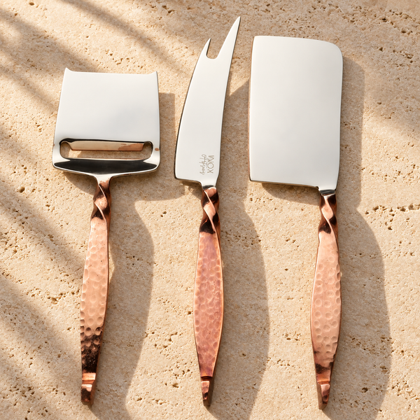 Hammered Copper-Handle Cheese Knife Set on a sunlit pale travertine counter