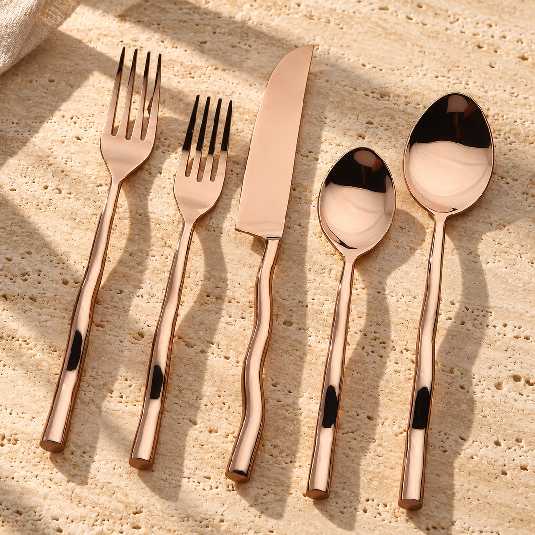Wavy Handle PVD Bronze Flatware Set on a sunlit pale travertine counter