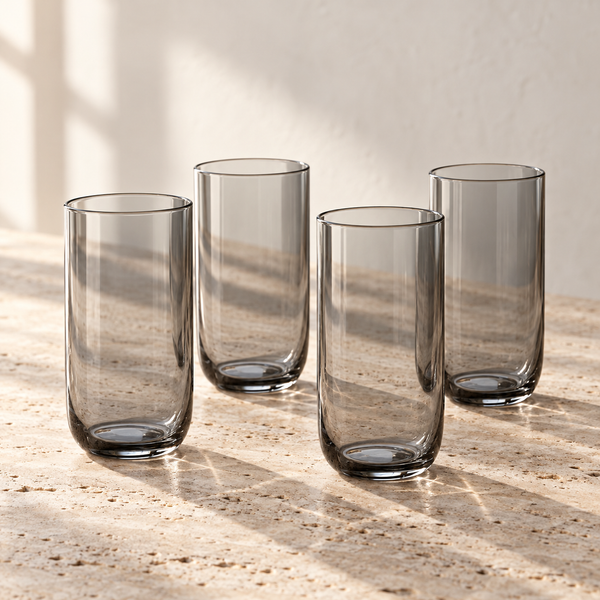 Smoke-Tinted Glass Tumbler Set empty on honed travertine in warm side light