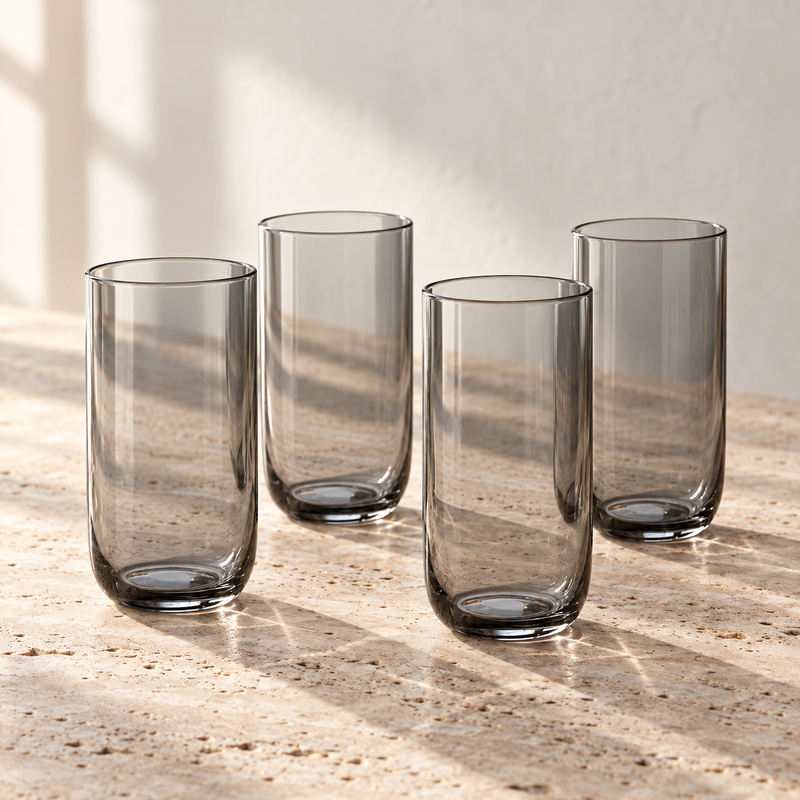 Smoke-Tinted Glass Tumbler Set empty on honed travertine in warm side light