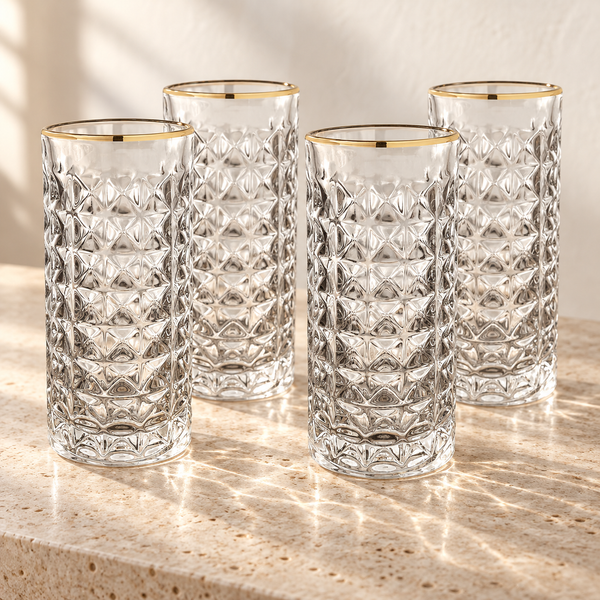 Gold-Rim Faceted Highball Glass Set empty on honed travertine in warm side light