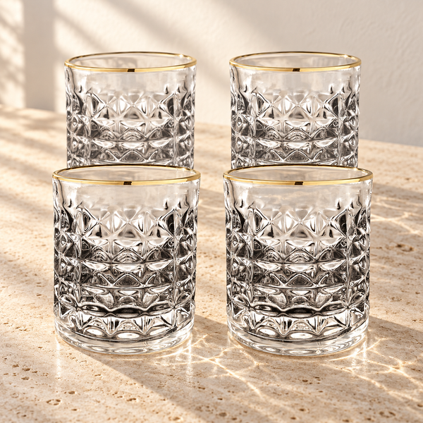 Gold-Rimmed Faceted Lowball Glass Set empty on honed travertine in warm side light