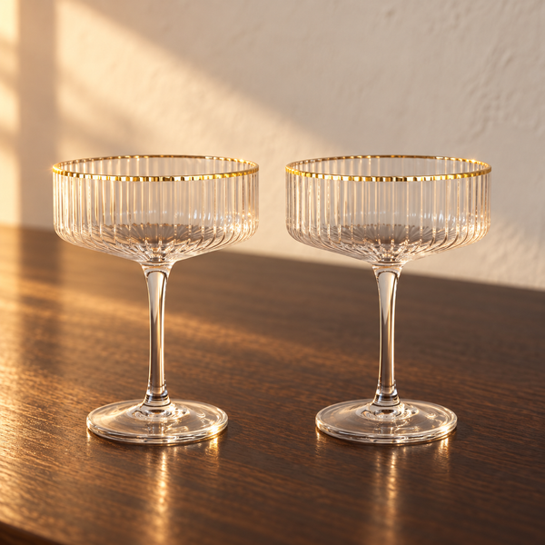 Ribbed Crystal Gold-Rim Coupe Set empty on an espresso walnut bar top in warm side light