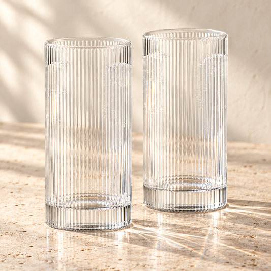 Ribbed Clear Glass Highball Tumblers empty on honed travertine in warm side light