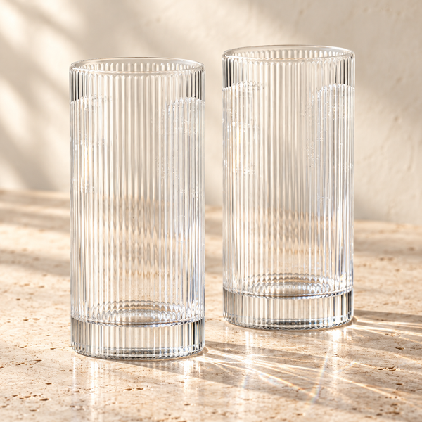 Ribbed Clear Glass Highball Tumblers empty on honed travertine in warm side light