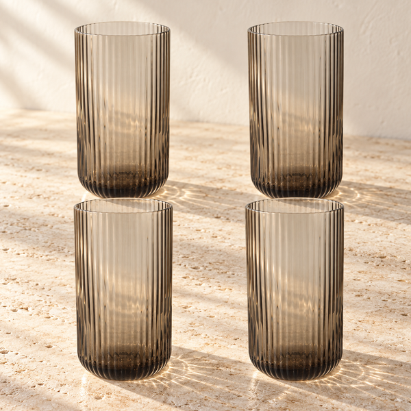 Fluted Smoke Glass Tumbler Set empty on honed travertine in warm side light